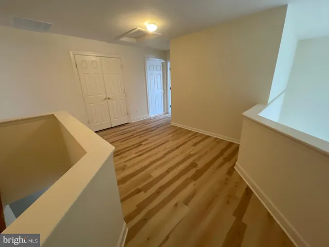 a view of an empty room with wooden floor and windows