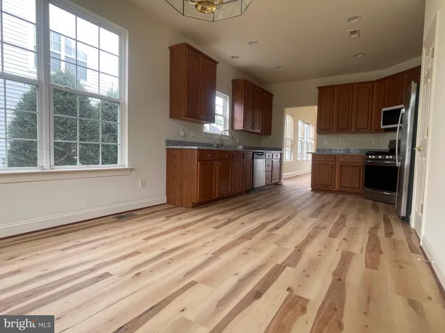 a large kitchen with kitchen island granite countertop a stove top oven a sink a counter space and cabinets