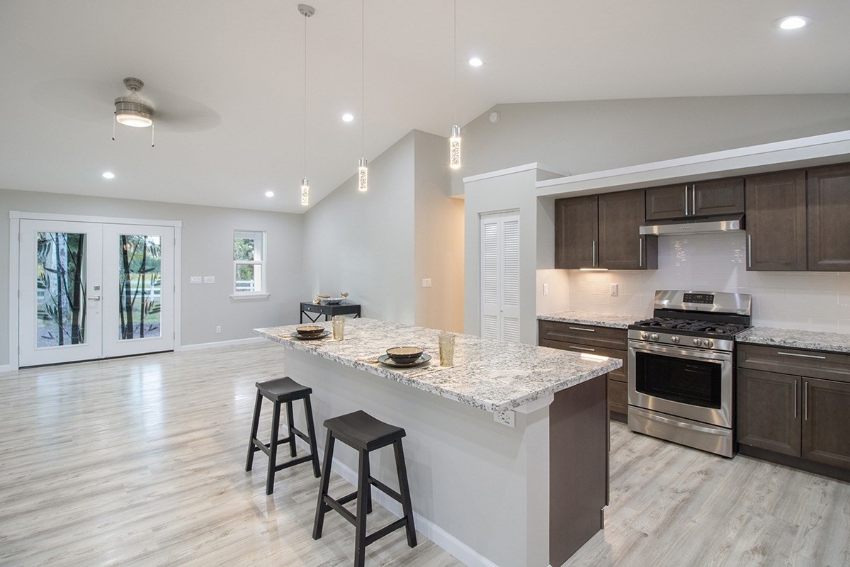 17-4437 S Road Mountain View, HI 96771 - Photo 3 of 30 a kitchen with stainless steel appliances kitchen island granite countertop a stove a sink a refrigerator and white cabinets with wooden floor
