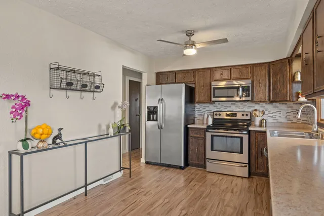 a kitchen with granite countertop stainless steel appliances a stove a refrigerator cabinets and a wooden floor