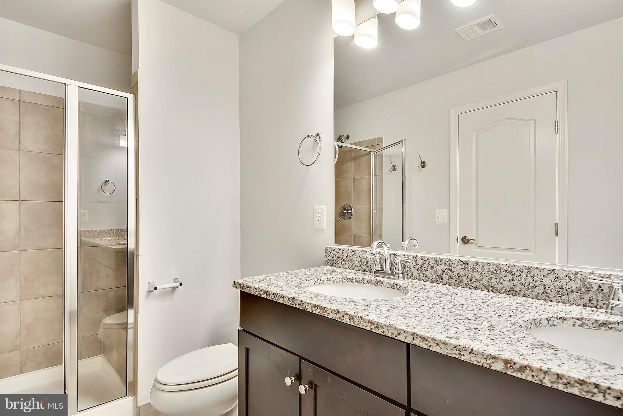 22652 Gray Falcon Square Ashburn, VA 20148 - Photo 15 of 24 a bathroom with a granite countertop sink a toilet and shower