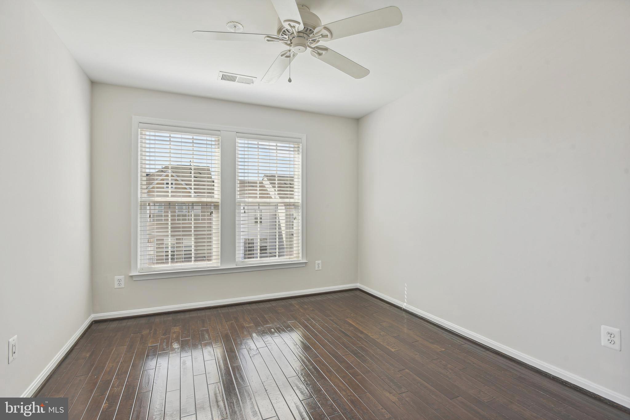 22652 Gray Falcon Square Ashburn, VA 20148 - Photo 18 of 24 an empty room with wooden floor chandelier fan and windows