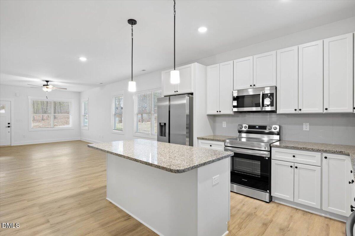 929 Jasmine Road Fuquay-Varina, NC 27526 - Photo 6 of 27 a kitchen with stainless steel appliances granite countertop a sink a stove a refrigerator and island with wooden floor