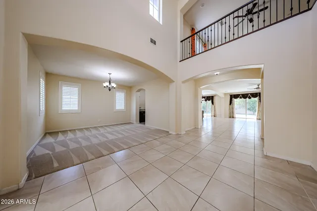 a view of an empty room with chandelier fan and wooden floor