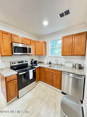 a kitchen with stainless steel appliances granite countertop a stove top oven a sink dishwasher a dining table and chairs with wooden floor