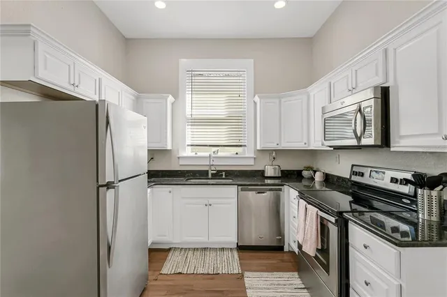 a kitchen with granite countertop a refrigerator stove and sink