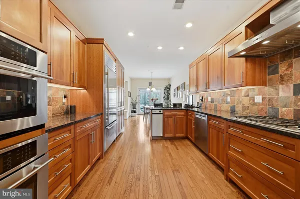 a kitchen with stainless steel appliances wooden floor sink and wooden cabinets