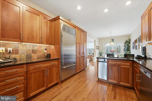 a kitchen with stainless steel appliances wooden floor sink and wooden cabinets