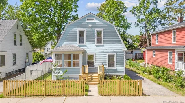 a view of a house with a small yard plants and large tree