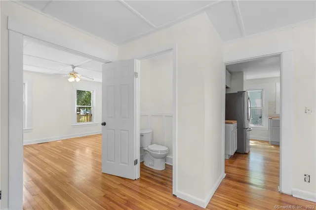 a view of a hallway with wooden floor and a bathroom