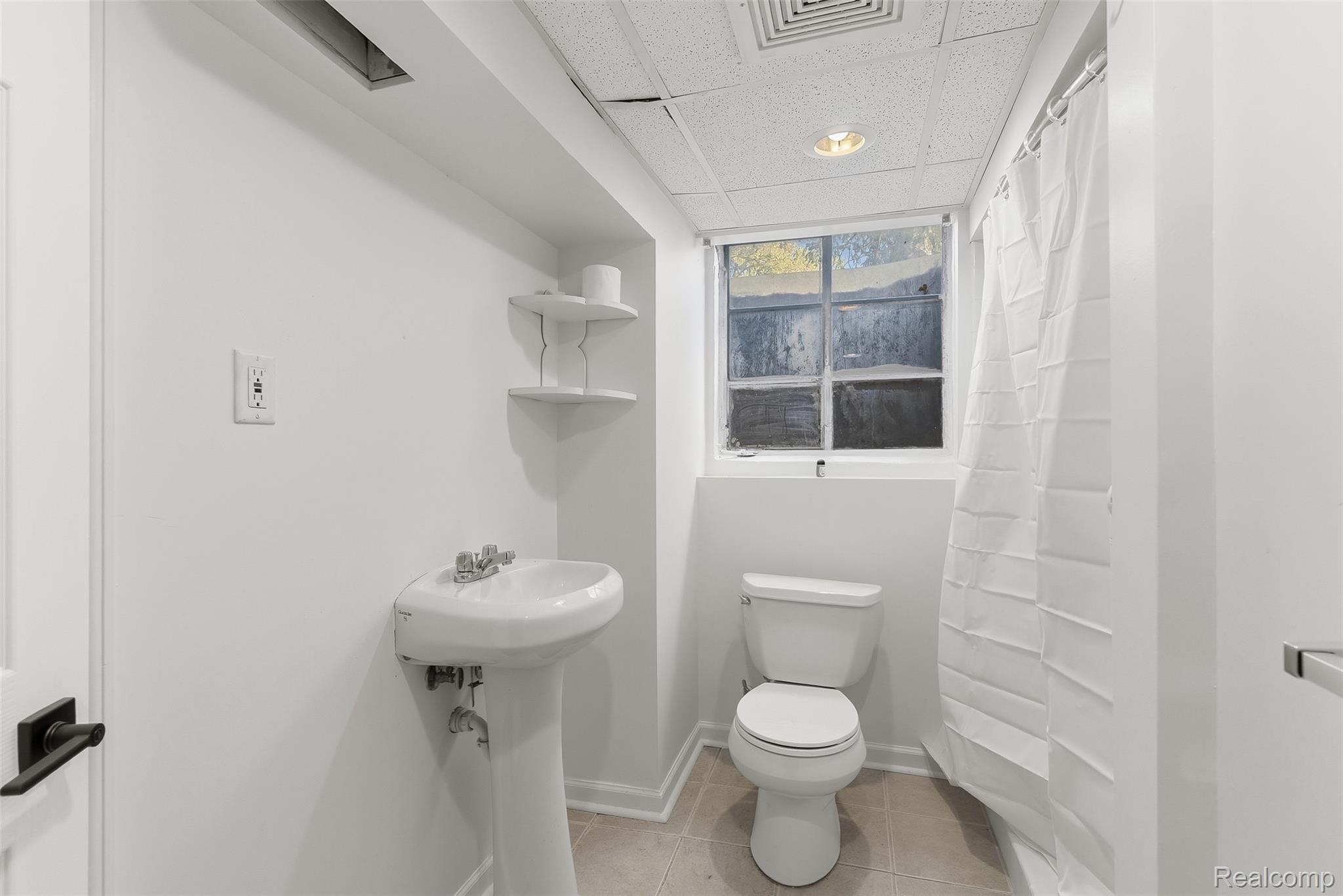 9101 Merriman Road Livonia, MI 48150 - Photo 33 of 41 Pedestal sink with chrome fixtures, window with natural light, drop ceiling with recessed lighting, tiled flooring, and a shower with a privacy curtain