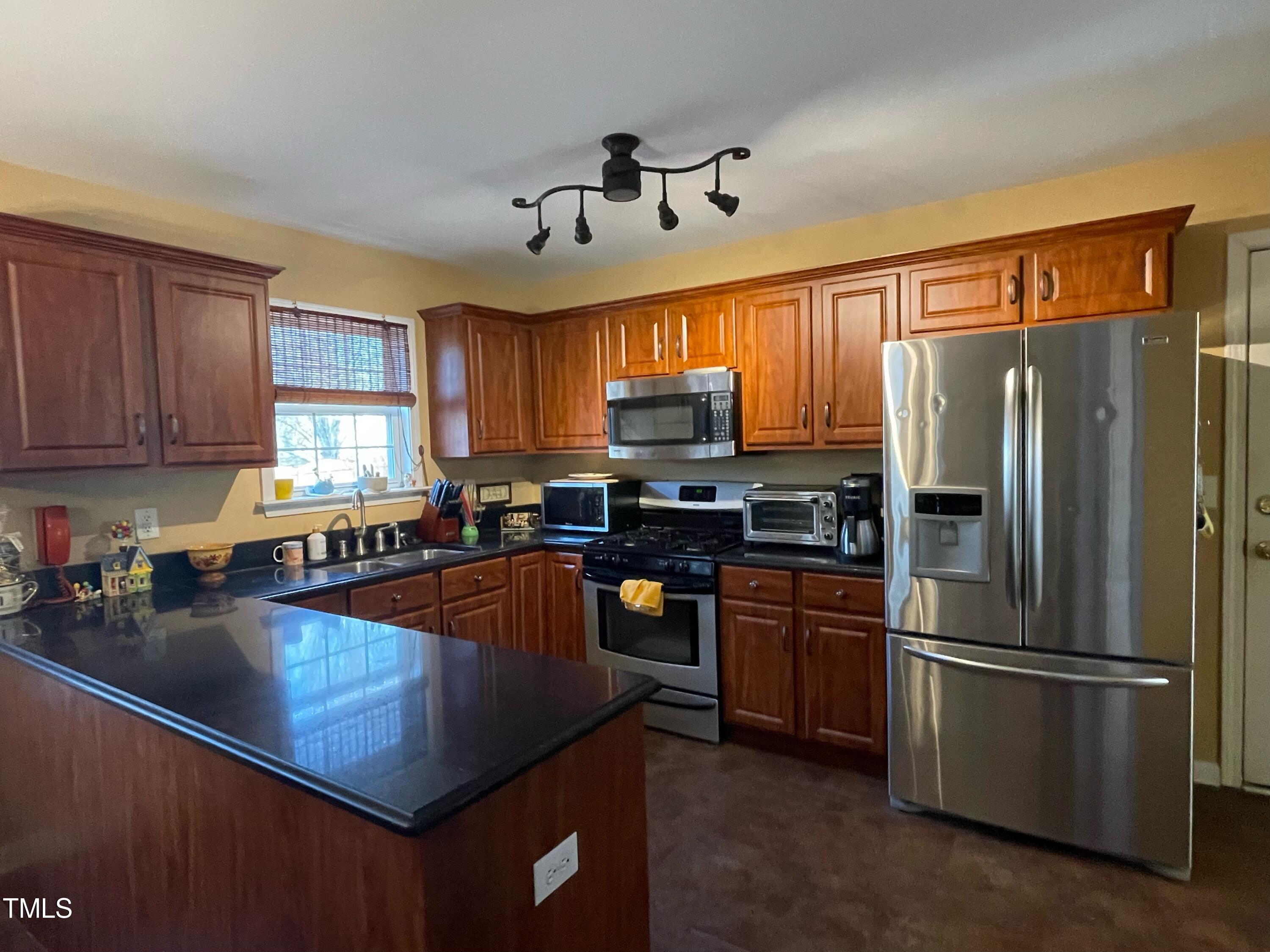 112 Grassy Valley Road Holly Springs, NC 27540 - Photo 11 of 39 a kitchen with granite countertop stainless steel appliances a refrigerator a stove top oven a sink dishwasher and wooden cabinets