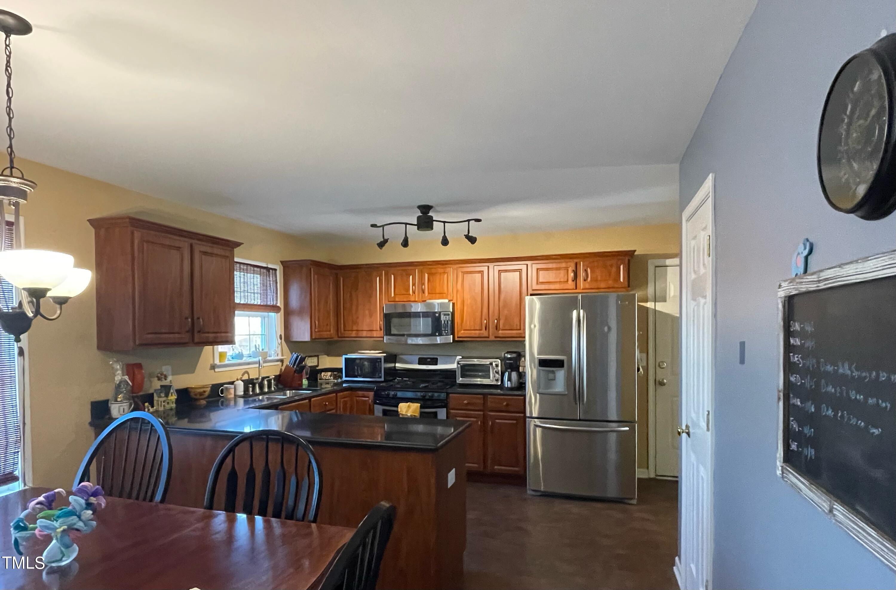 112 Grassy Valley Road Holly Springs, NC 27540 - Photo 12 of 39 a kitchen with stainless steel appliances granite countertop a refrigerator a stove a sink a dining table and chairs with wooden floor