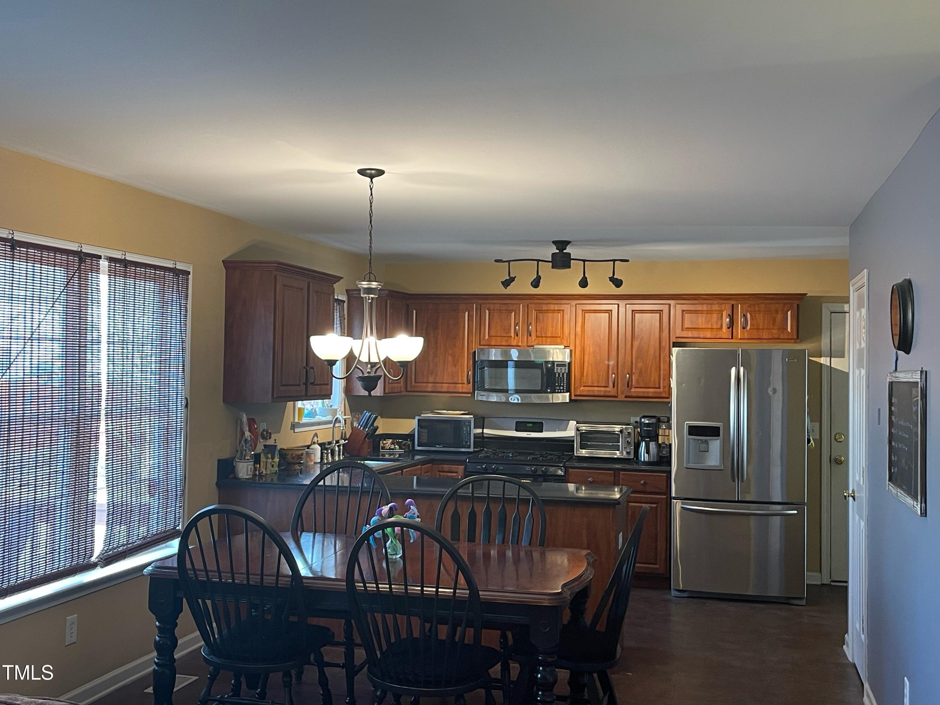 112 Grassy Valley Road Holly Springs, NC 27540 - Photo 13 of 39 a kitchen with refrigerator a dining table and chairs