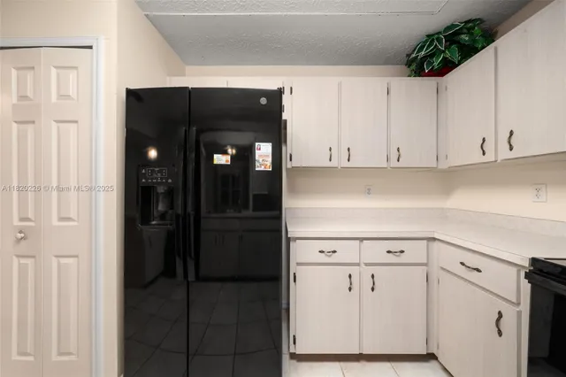a kitchen with white cabinets and refrigerator