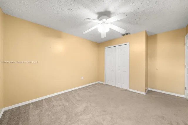 a view of an empty room with window and chandelier fan