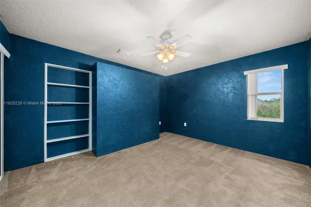 a backyard of a house with plants and large tree