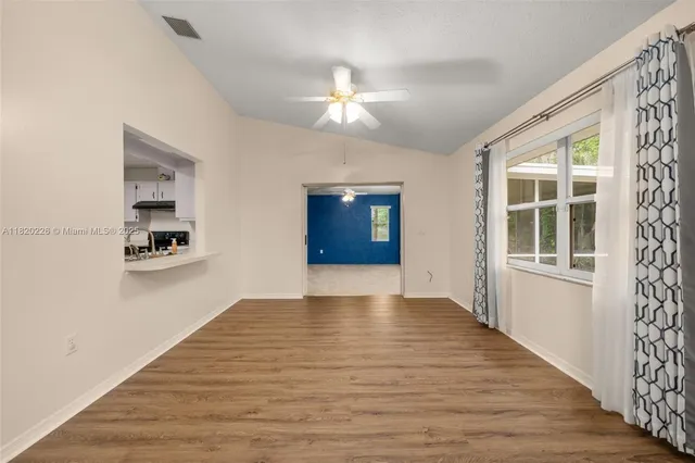 a view of an empty room with a window and wooden floor
