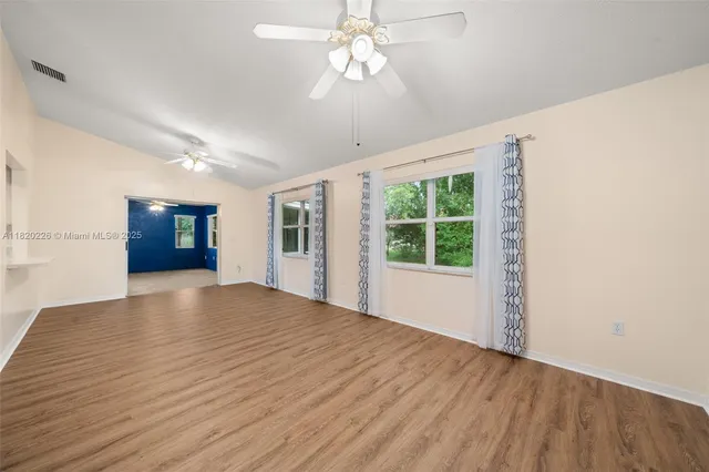 a view of an empty room with window and wooden floor