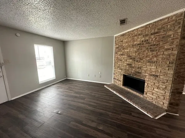 an empty room with wooden floor fireplace and windows