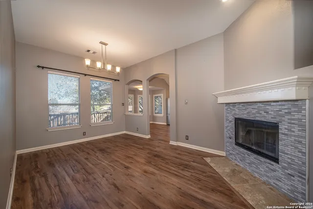 a view of an empty room with wooden floor fireplace and a window