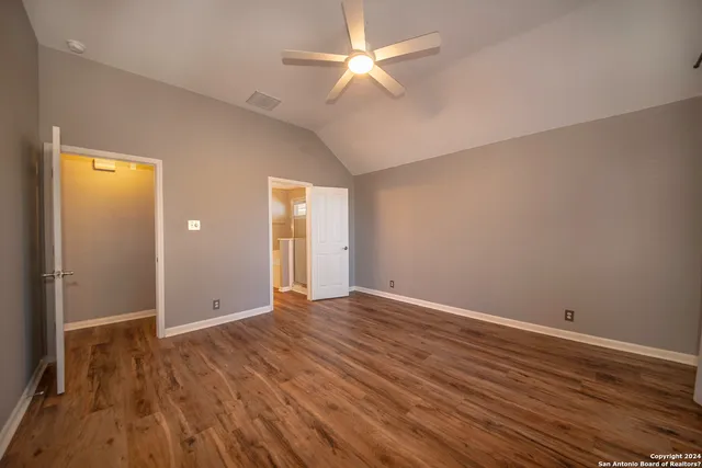 an empty room with wooden floor and a ceiling fan