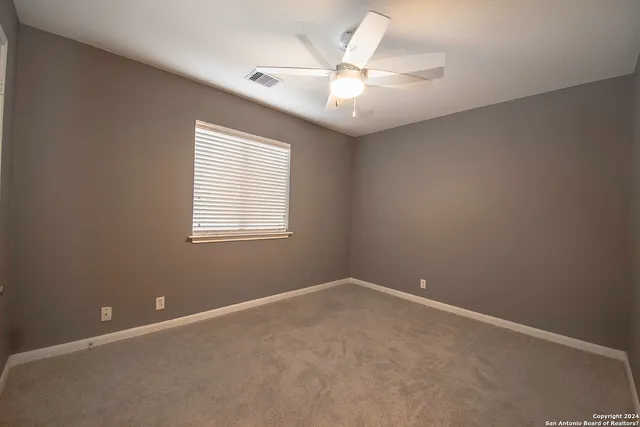 an empty room with a window and a fan