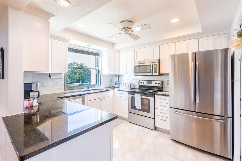 5014 Marsh Field Road, Unit 30 Sarasota, FL 34235 - Photo 7 of 9 a kitchen with stainless steel appliances granite countertop a refrigerator a stove a sink a center island and a window