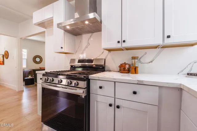 a kitchen with stainless steel appliances granite countertop a stove a sink and white cabinets