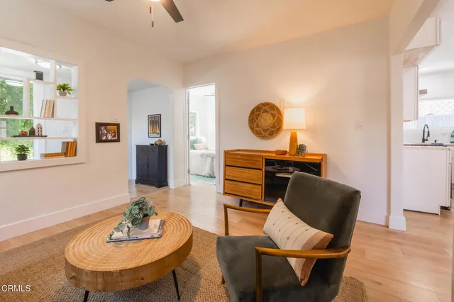 a living room with furniture a clock on wall and a window
