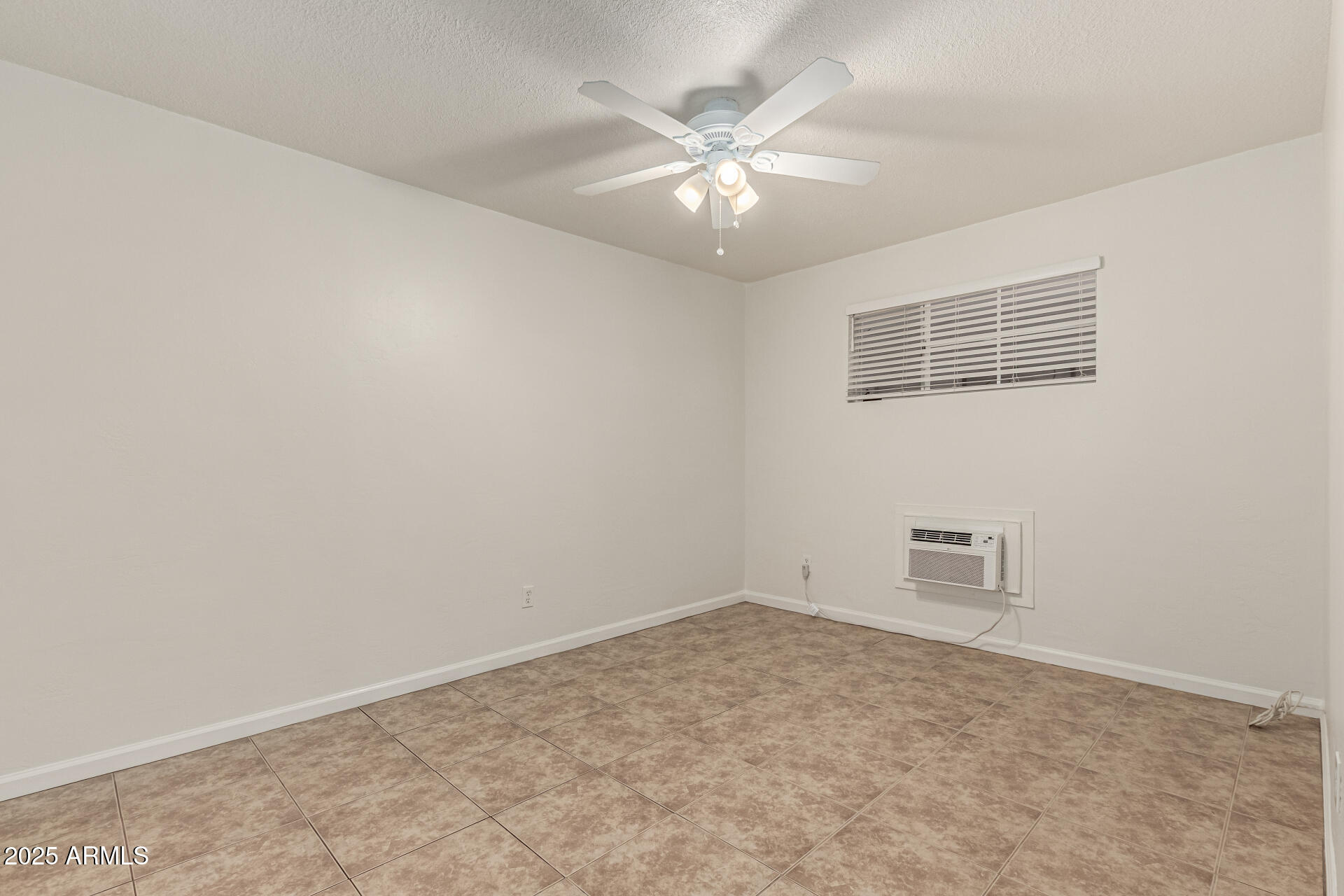 3540 East Montecito Avenue, Unit 3 Phoenix, AZ 85018 - Photo 15 of 23 an empty room with a chandelier fan and windows