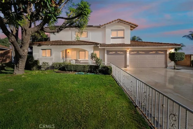 a view of a house with a small yard and a large tree