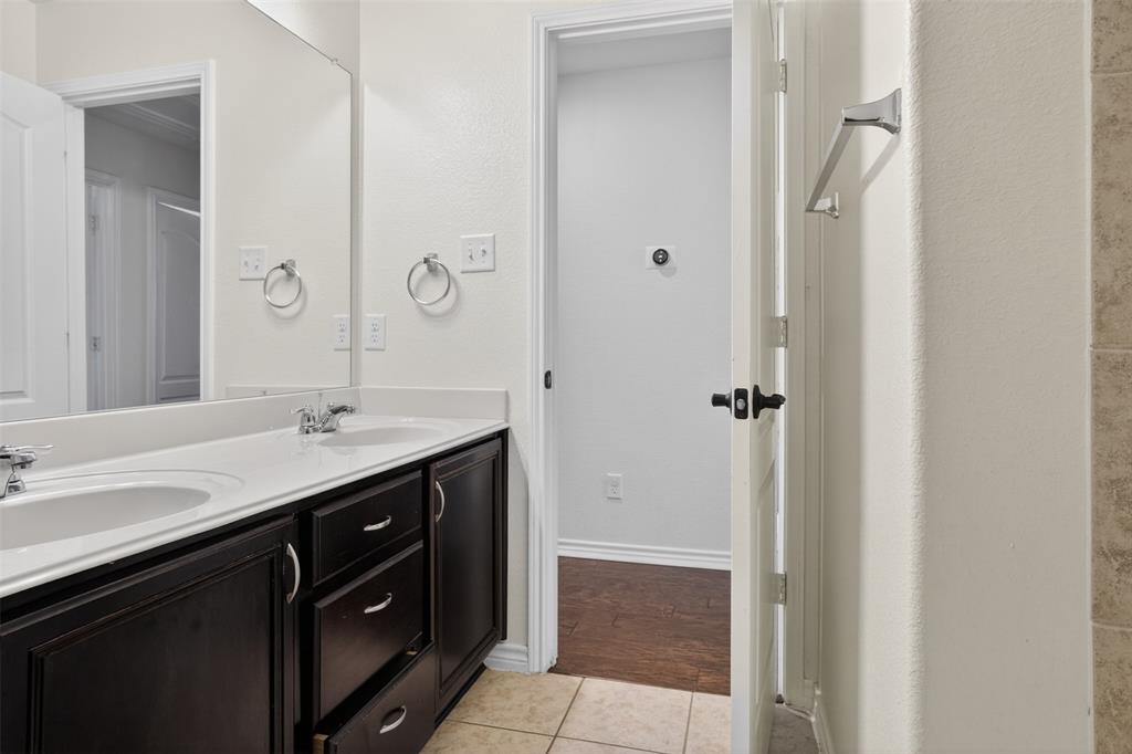 8728 Maple Ridge Trail Fort Worth, TX 76244 - Photo 27 of 40 Bathroom featuring a double vanity with dark wood cabinetry, white countertops, dual sinks with chrome fixtures, and a large wall-mounted mirror