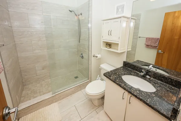 a bathroom with a granite countertop sink a toilet and shower