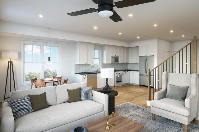 a living room with stainless steel appliances furniture and a kitchen view