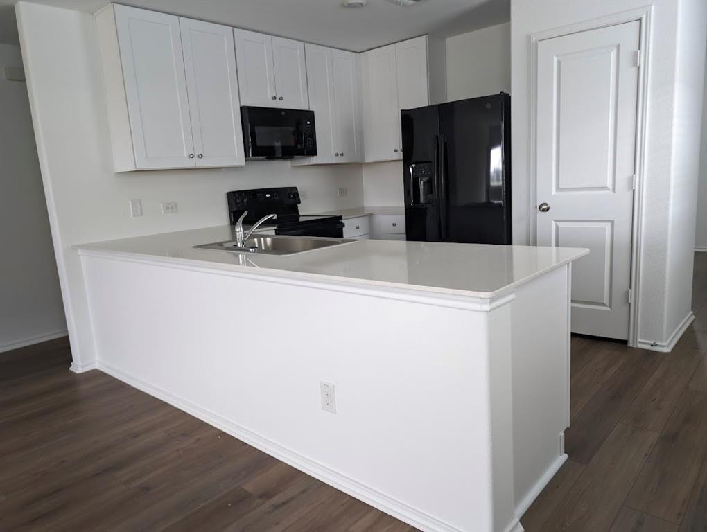 564 Rancho Del Cielo Loop Jarrell, TX 76537 - Photo 3 of 14 A well-appointed kitchen features dark wood-style flooring and bright white cabinetry.