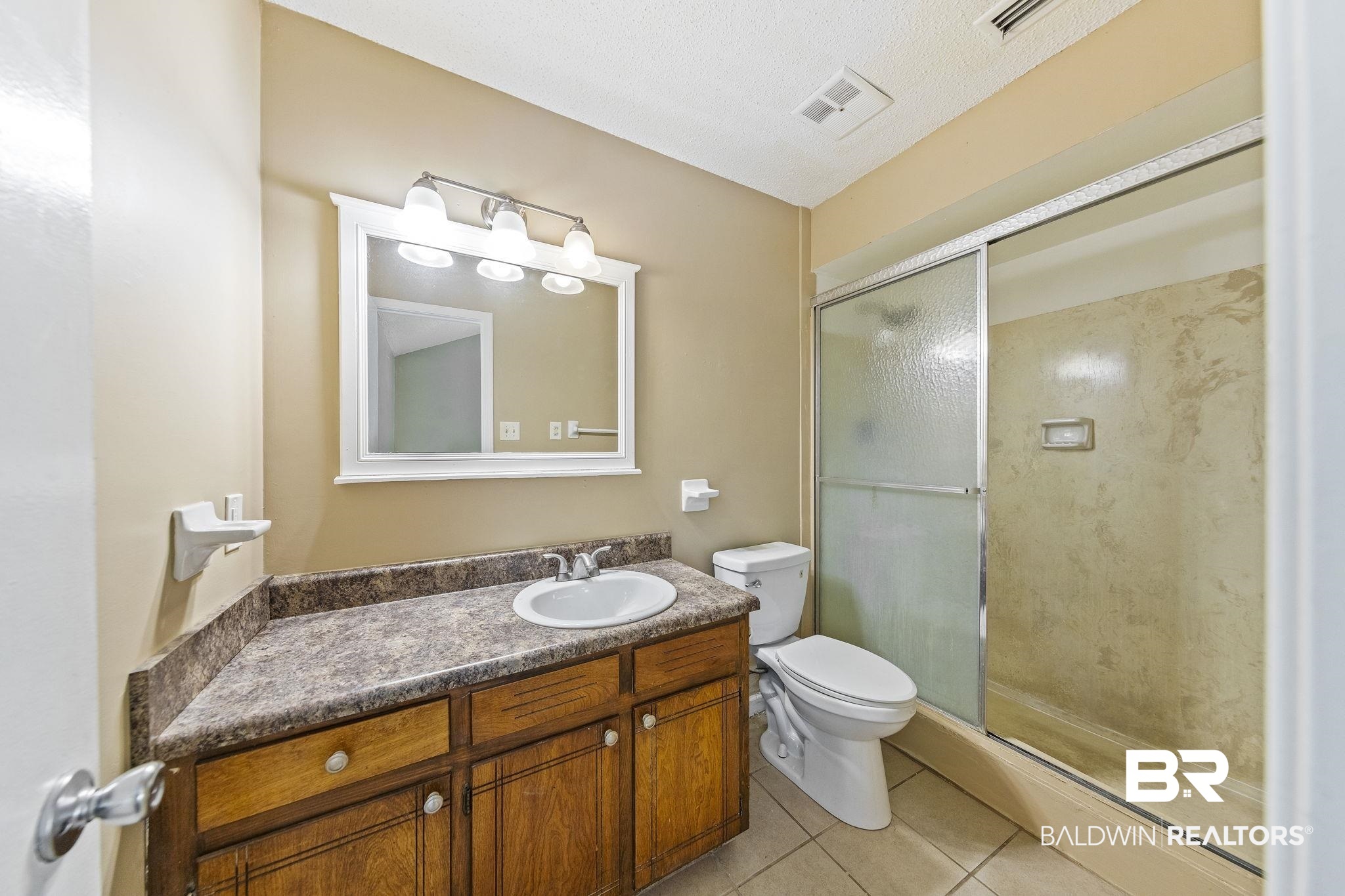 4151 Springdale Road Mobile, AL 36609 - Photo 11 of 21 Bathroom featuring vanity, a textured ceiling, tile patterned flooring, toilet, and an enclosed shower