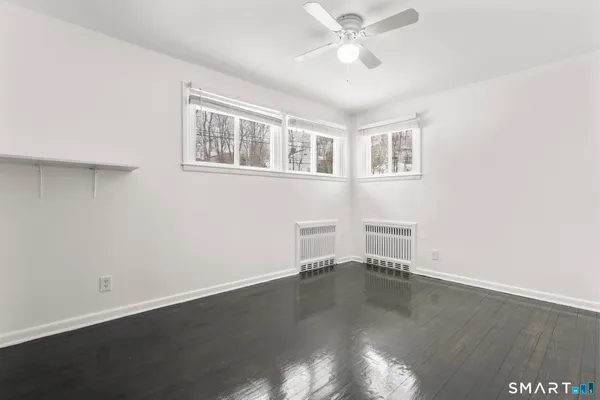 a view of empty room with wooden floor and fan
