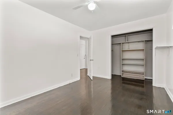 a view of an empty room with a window and wooden floor