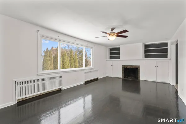 an empty room with windows fireplace and a ceiling fan