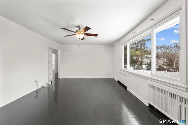an empty room with windows and chandelier fan