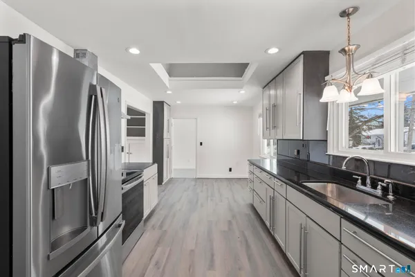a kitchen with granite countertop a refrigerator a sink a stove and oven