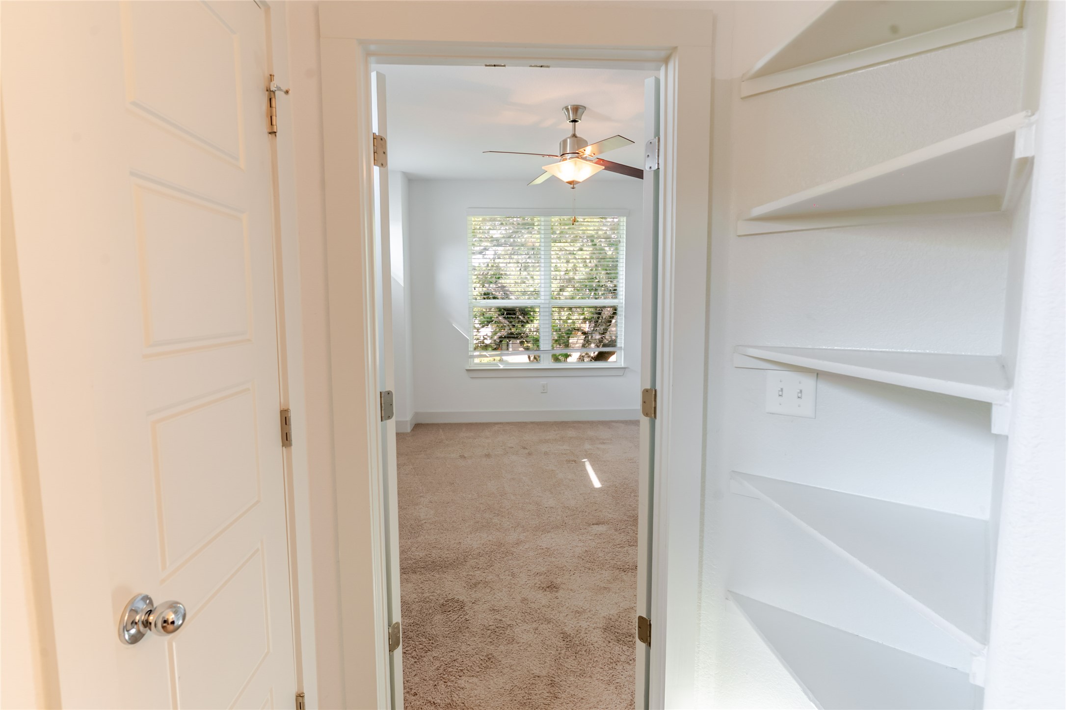 1400 Homespun Road Austin, TX 78745 - Photo 15 of 30 Built-in shelving lines the hallway leading directly into a carpeted bedroom filled with natural light.
