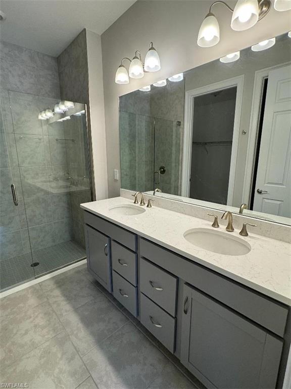 926 Enbrook Loop Naples, FL 34114 - Photo 16 of 24 Bathroom featuring a shower stall, tile patterned floors, double vanity, and a sink