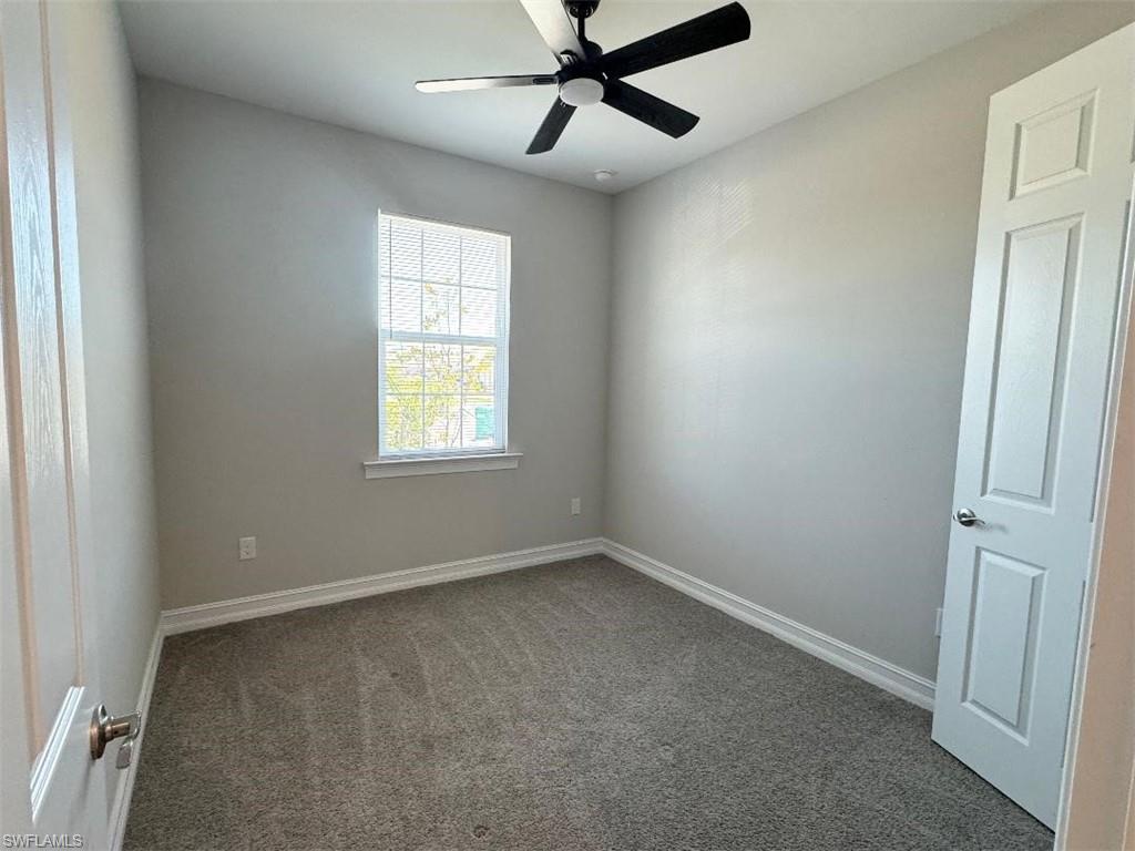 926 Enbrook Loop Naples, FL 34114 - Photo 19 of 24 Empty room featuring baseboards, dark carpet, and a ceiling fan