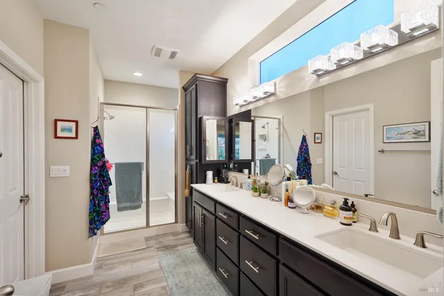 a bathroom with a double vanity sink mirror and shower