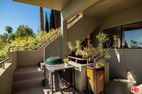 a living room with furniture a potted plant and kitchen view
