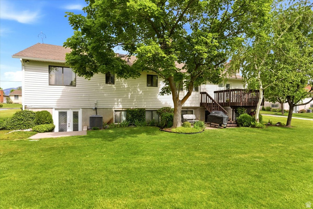 5321 South 3100th Street West Roy, UT 84067 - Photo 57 of 64 Expansive grassy backyard featuring mature trees, a multi-level wood deck, and a walk-out basement with double doors