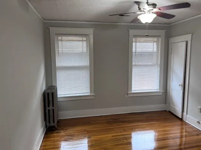 an empty room with wooden floor closet and windows