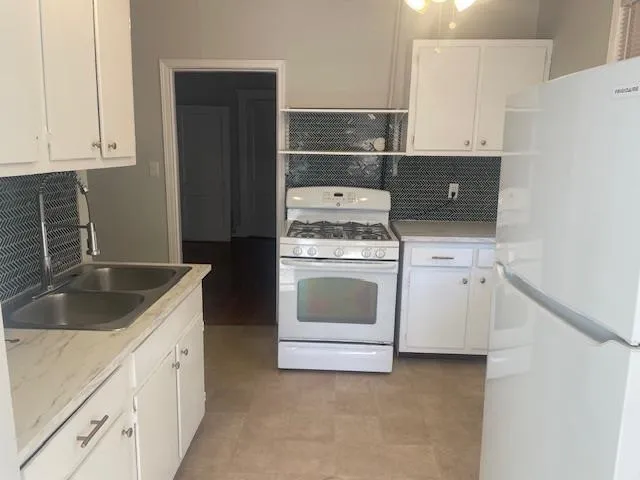 a kitchen with granite countertop white cabinets and white appliances